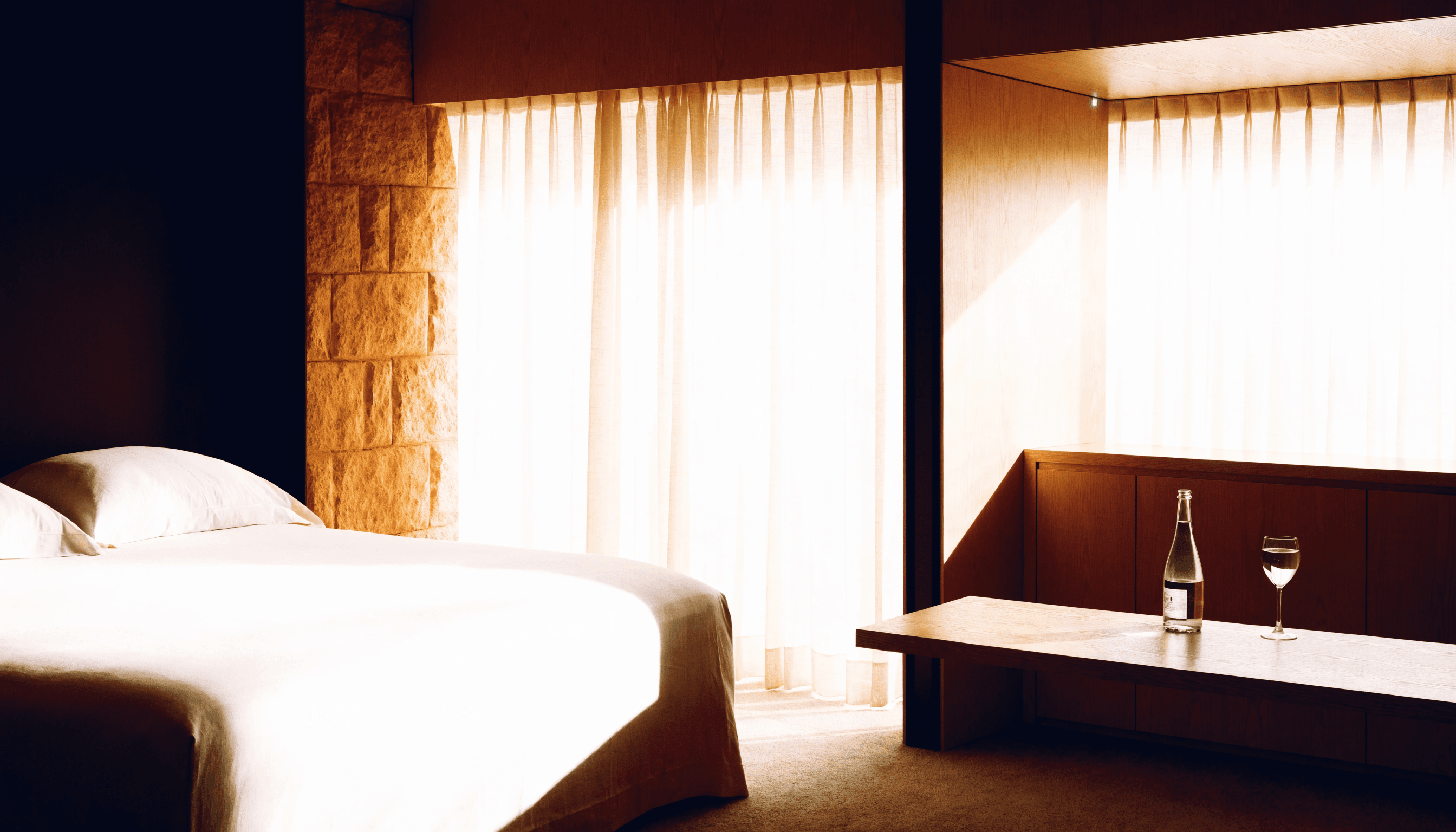 A prepared hotel suite with quiet bedding and sparkling water ready for a returning guest